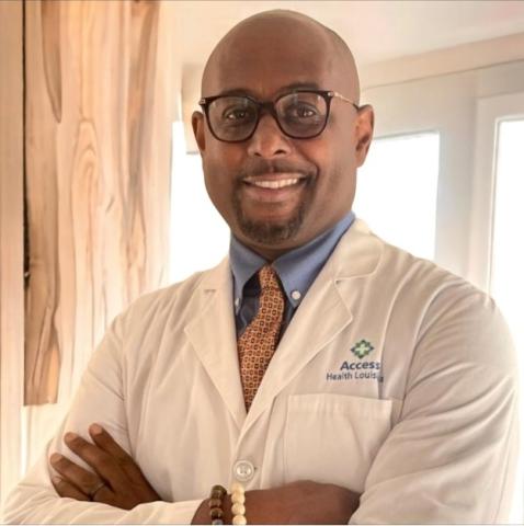 Smiling man in glasses and white lab coat, arms crossed.